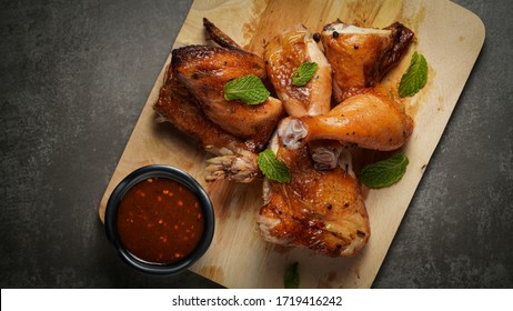 Röstetes Huhn auf Holzteller mit dunklem Hintergrund.