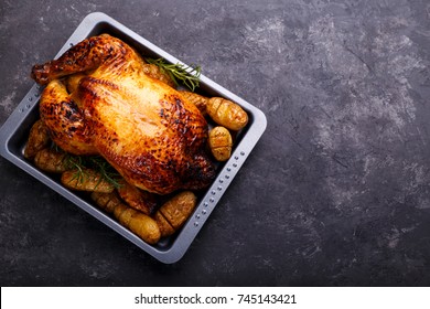 roasted chicken and potatoes on black slate stone background, flat lay with copy space. Menu or recipe template