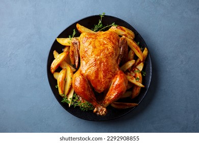 Roasted chicken with potatoes on dark plate. Grey background. Close up. Top view. - Shutterstock ID 2292908855