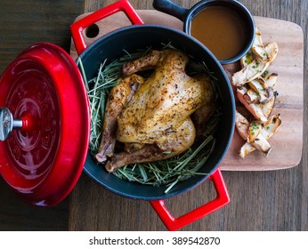 Roasted Chicken In Red Pot On Brown Table Close Up