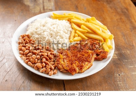 Roasted chicken thigh and drumstick, white rice, beans and french fries on sticks with selective focus