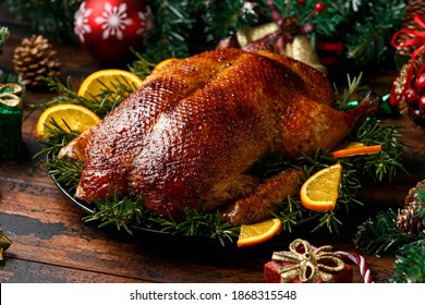 Roasted Christmas duck with decoration, gifts, green tree branch on wooden rustic table