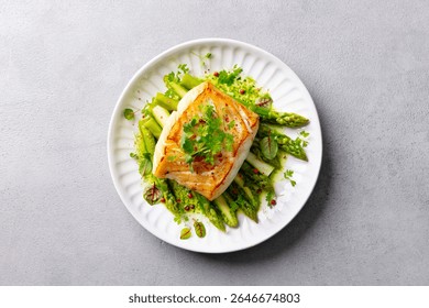 Roasted cod, codfish with asparagus and on plate. Grey background. Close up. Top view.