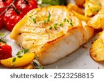 Roasted cod, codfish with baked potatoes and cherry tomatoes. Close up.