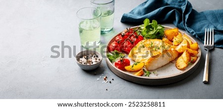 Roasted cod, codfish with baked potatoes and cherry tomatoes on plate. Grey background. Copy space.