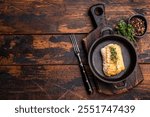 Roasted cod fish loin fiilet in skillet. Wooden background. top view.