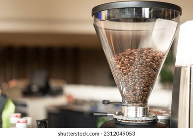 Roasted coffee beans in the automatic grinder machine at the coffee bar. Beverage ingredient object photo.
