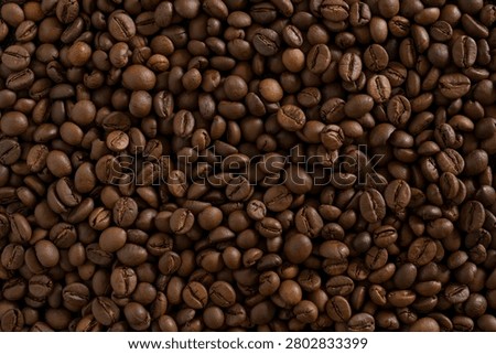 Roasted coffee beans background. Full frame close-up texture of dark brown aromatic coffee beans, ideal for wallpaper, banner, or food and drink backdrop.
