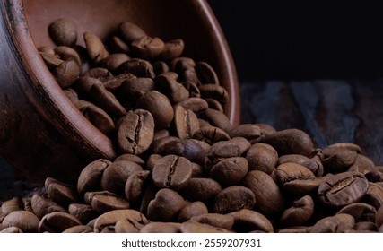 Roasted coffee beans pour out of a clay cup onto a wooden surface. Coffee beans in a clay cup. - Powered by Shutterstock