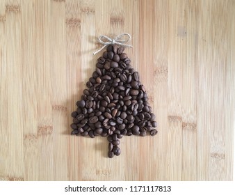 Roasted Coffee Beans Shaped Into Christmas Tree On Rustic Bamboo Wood Board, With Wood Cutout Angel, Twine Jute Bow As Tree Topper, Holiday Theme With Copy Space