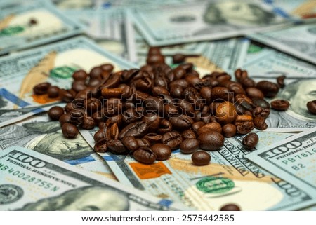 Roasted coffee beans are spread out on top of several one hundred dollar bills, creating a striking contrast between currency and a popular beverage.