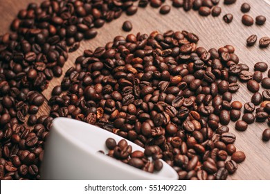 Roasted coffee beans in a white mug on a wooden table - Shutterstock ID 551409220