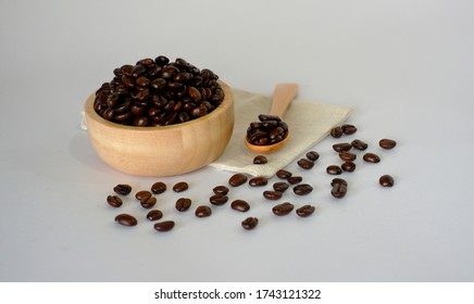 Roasted Coffee Beans In A Wooden Cup And Spoon Placed On A Calico, Translucent Background.