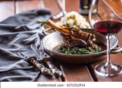 Roasted or confit Lamb Leg in pan with spinach and red wine.