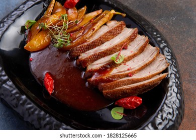 Roasted Duck And Caramelized Pear In A Dark Plate