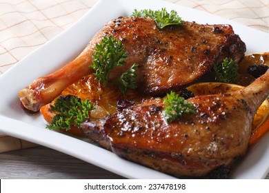 roasted duck leg with oranges on a white plate close up. horizontal 