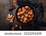 Roasted edible sweet chestnuts in iron pan on wooden table