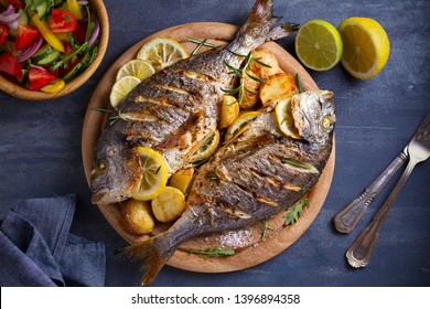 Roasted fish and potatoes, served on wooden tray. overhead, horizontal - image - Shutterstock ID 1396894358
