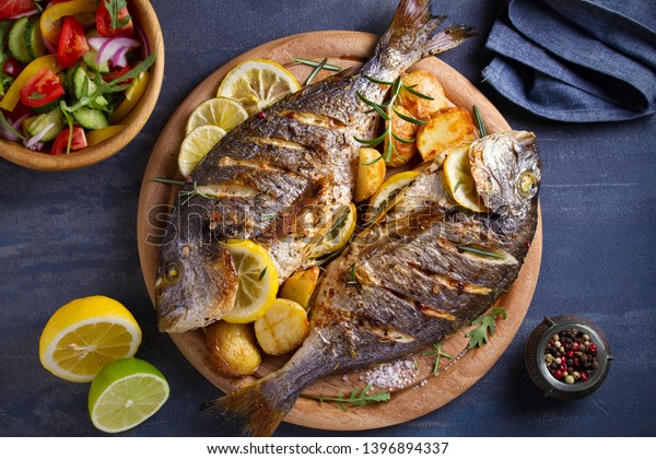 Roasted fish and potatoes, served on wooden tray.\
overhead, horizontal -\
image