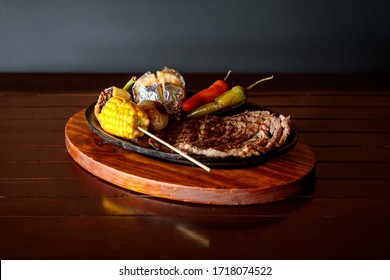 Roasted Flank Steak With Chili Peppers And Baked Potato On A Wooden Board