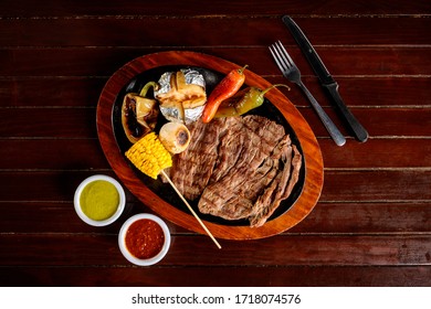 Roasted Flank Steak With Chili Peppers And Baked Potato On A Wooden Board