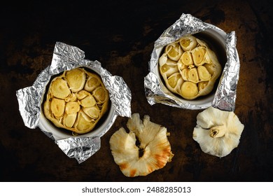 Roasted Garlic Bulbs in Ramekins Covered with Foil: Two heads of garlic that have been roasted in olive oil inside small ceramic bowls - Powered by Shutterstock