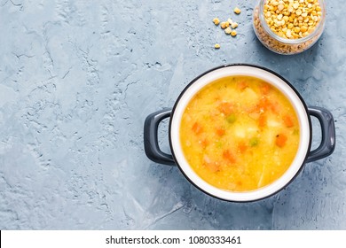 Roasted garlic split pea soup in a pot on blue concrete background. Top view, copy space.