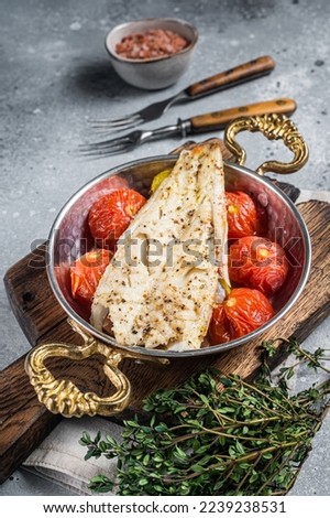 Roasted Haddock fish fillet in skillet with tomato and potato. Gray background. Top view. Foto d'archivio © 