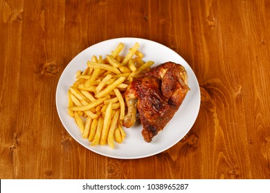roasted half chicken, traditional bavarian dish with french fries on wooden table, copy space