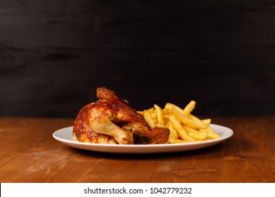 roasted half chicken, traditional bavarian dish with french fries on wooden table, and black copy space
