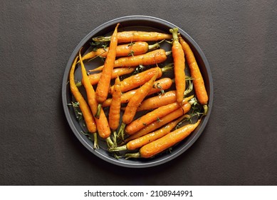 Roasted Honey Glazed Carrots On Plate Over Dark Stone Background. Top View, Flat Lay