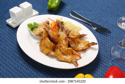 Roasted Jumbo Prawns  With Salt, Pepper, Sauce  And Fresh Vegetables On White Oval Plate, Isolated On Blue Background, Low Angle Back Side View, Macro Close-up Focus At The Middle Of Food 