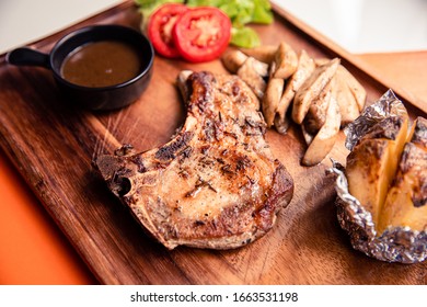 Roasted kurobuta pork chop with sauteed mushroom, potato wedges and black pepper gravy sauce on wooden cutting board - Powered by Shutterstock