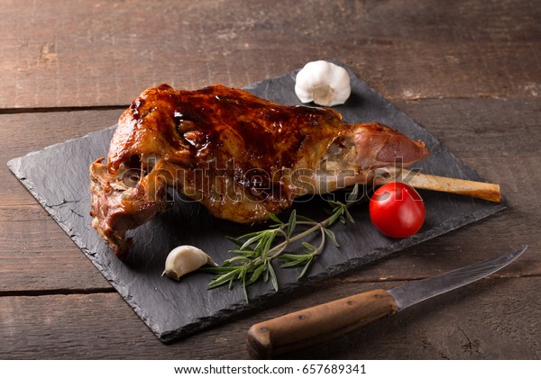 Roasted lamb leg on wooden\
table
