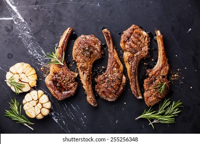 Roasted lamb ribs with spices and garlic on black marble background