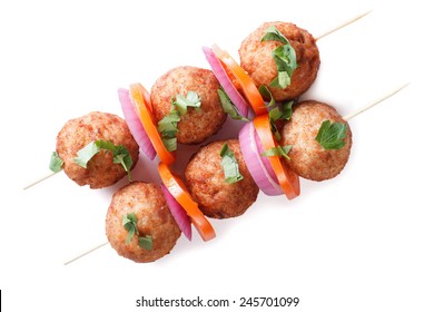 Roasted meatballs on skewers with fresh vegetables isolated on white background. horizontal view from above 