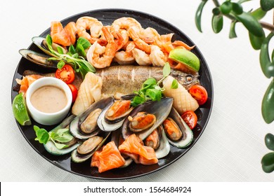 Roasted Mixed Seafood Contain Mussels, prawns, salmon, Calamari Squids and Grilled Barracuda Fish Garlic with Spicy Chili Sauce. Isolated on White Background. Seafood and meat platter. Mediterranean