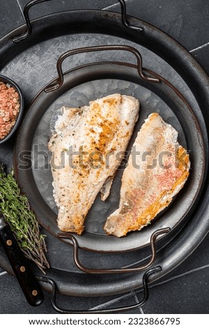 Roasted ocean red perch fillet with olive oil, thyme and spices. Black background. Top view.