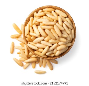 Roasted pine nuts in the wooden bowl. isolated on white background, top view.