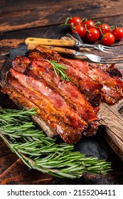 Roasted pork Bacon sizzling slices on wooden board. Wooden background. Top view.