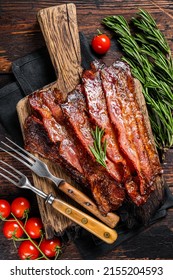 Roasted pork Bacon sizzling slices on wooden board. Wooden background. Top view.