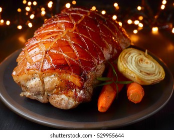 Roasted Pork And Vegetables On Christmas Lights Background