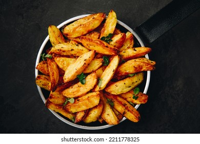 Roasted potatoes. Baked potato wedges in frying pan on dark stone background. Top view with copy space. - Powered by Shutterstock