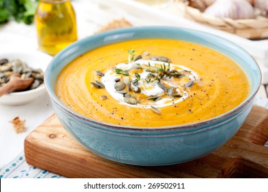 Roasted pumpkin and carrot soup with cream and pumpkin seeds on white wooden background. Copy space - Powered by Shutterstock