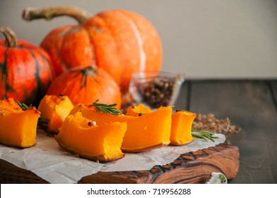 Roasted pumpkin slices with rosemary and dry thyme on a baking paper on a wooden background.  - Shutterstock ID 719956288