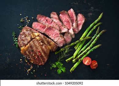 Roasted rib eye steak with green asparagus on old sheet