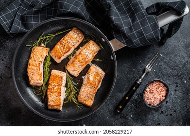Roasted Salmon Fillet Steak in a pan with rosemary. Black background. Top view