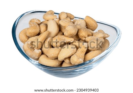 Roasted salted cashew nuts in glass bowl isolated on white background. Anacardium occidentale. Closeup an oval transparent dish full of yummy salty flavored cashews. Culinary nosh of edible bio seeds.