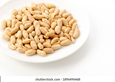 Roasted salted peanuts on a white plate on a white background
