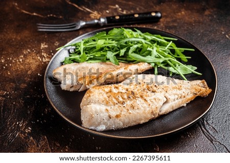 Roasted Snapper, sea red perch fillet on a plate with salad. Dark background. Top view.